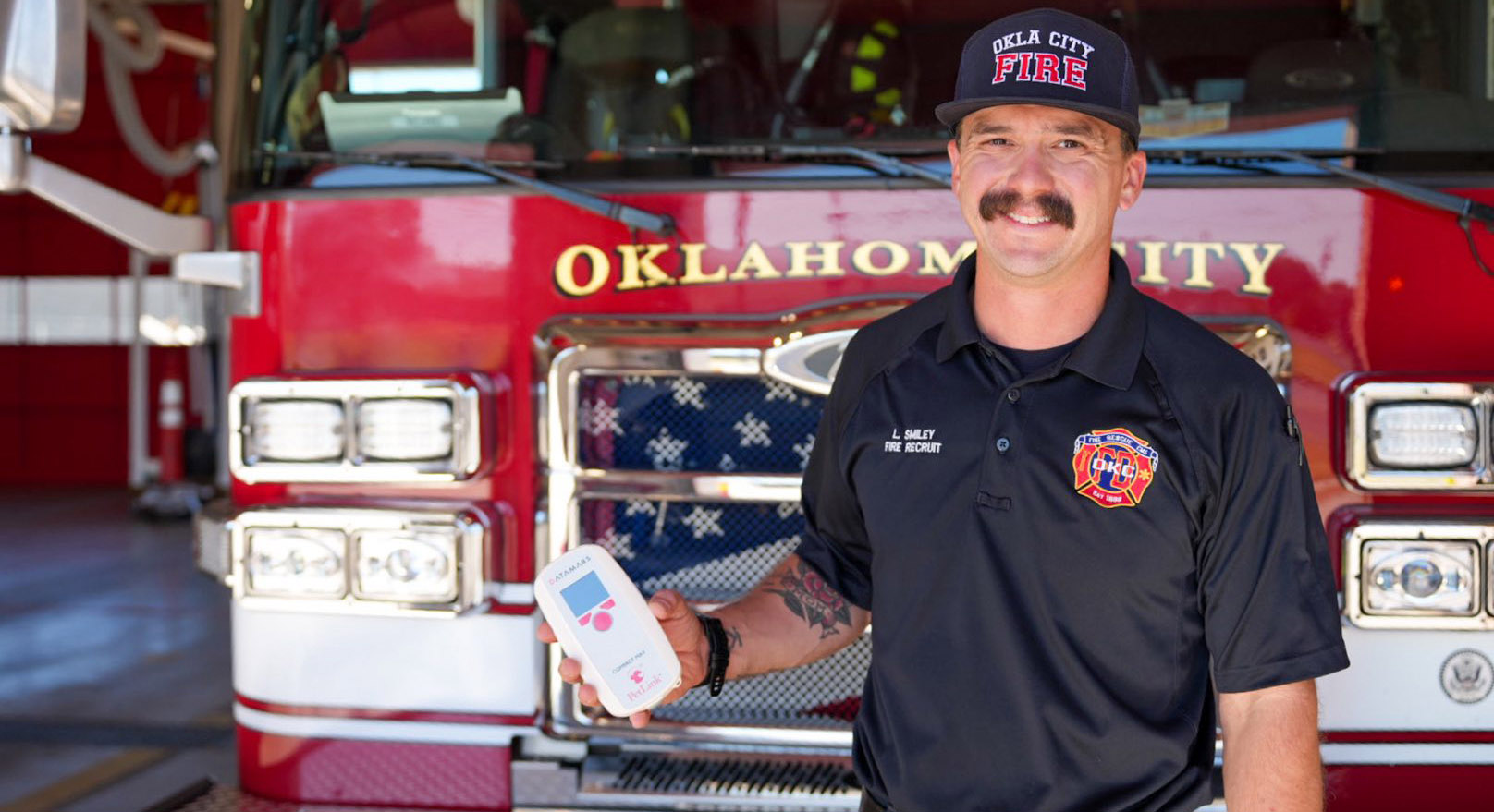 firefighter holding microchip reader in front of fire truck