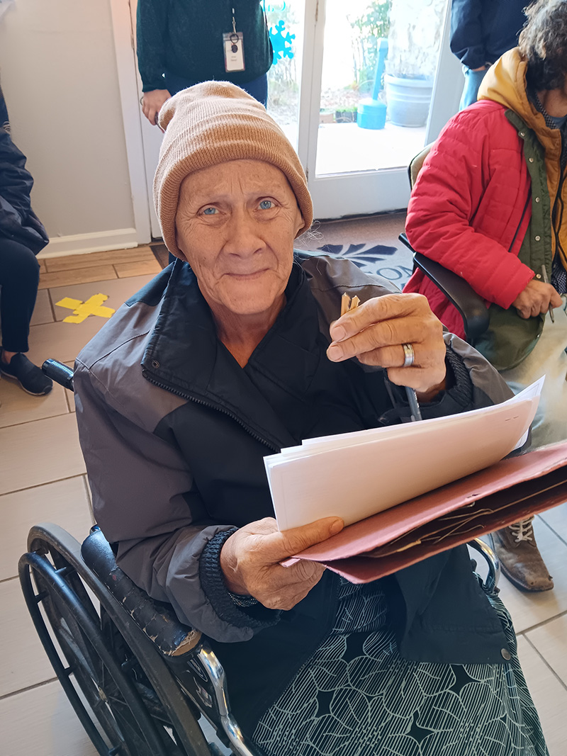 elderly woman in wheelchair holding key and papers to new home