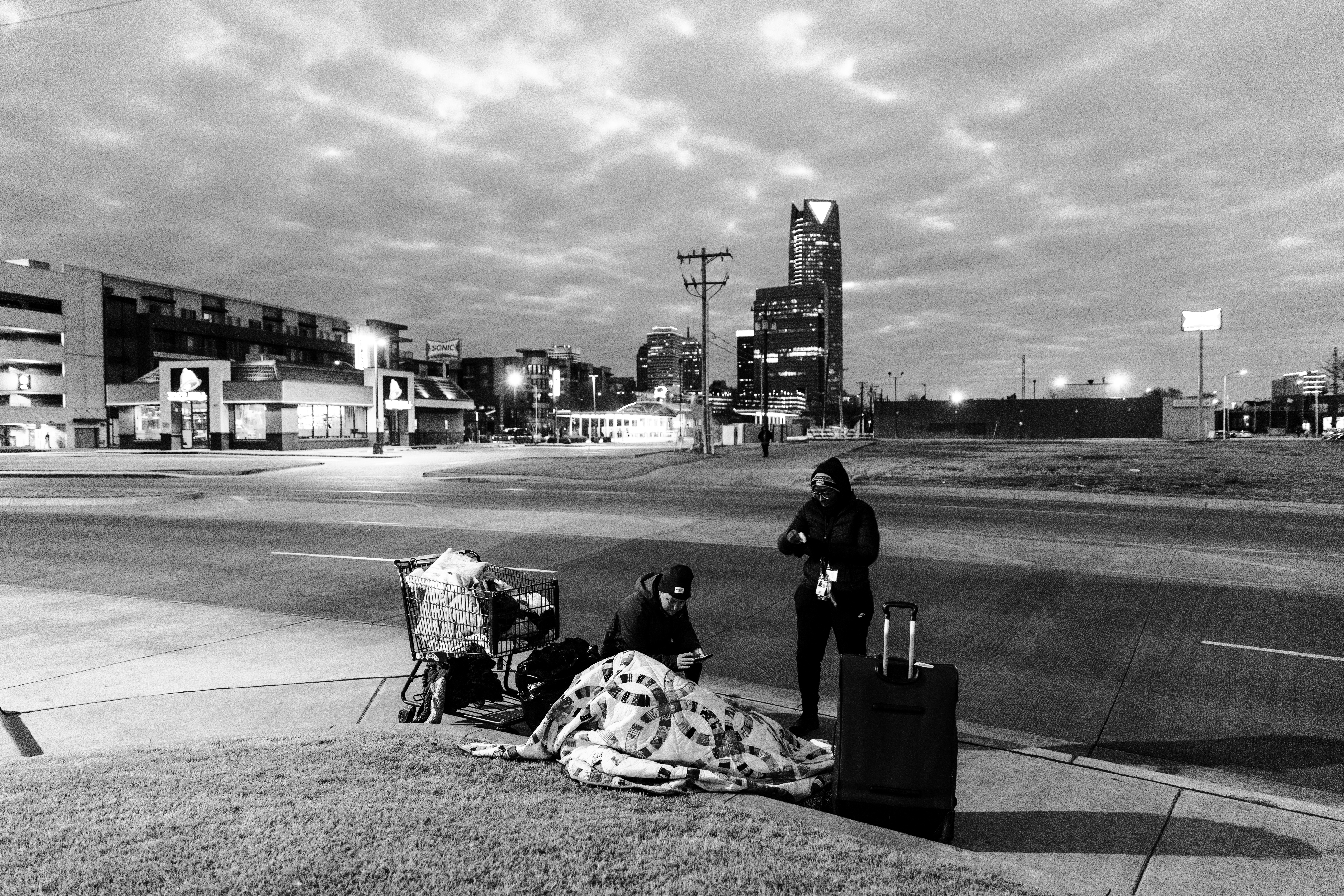 black and white photo of volunteers talking to person on the ground wrapped in a blanket
