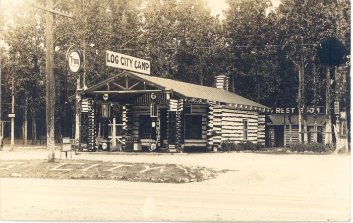 log cabin near trees and road