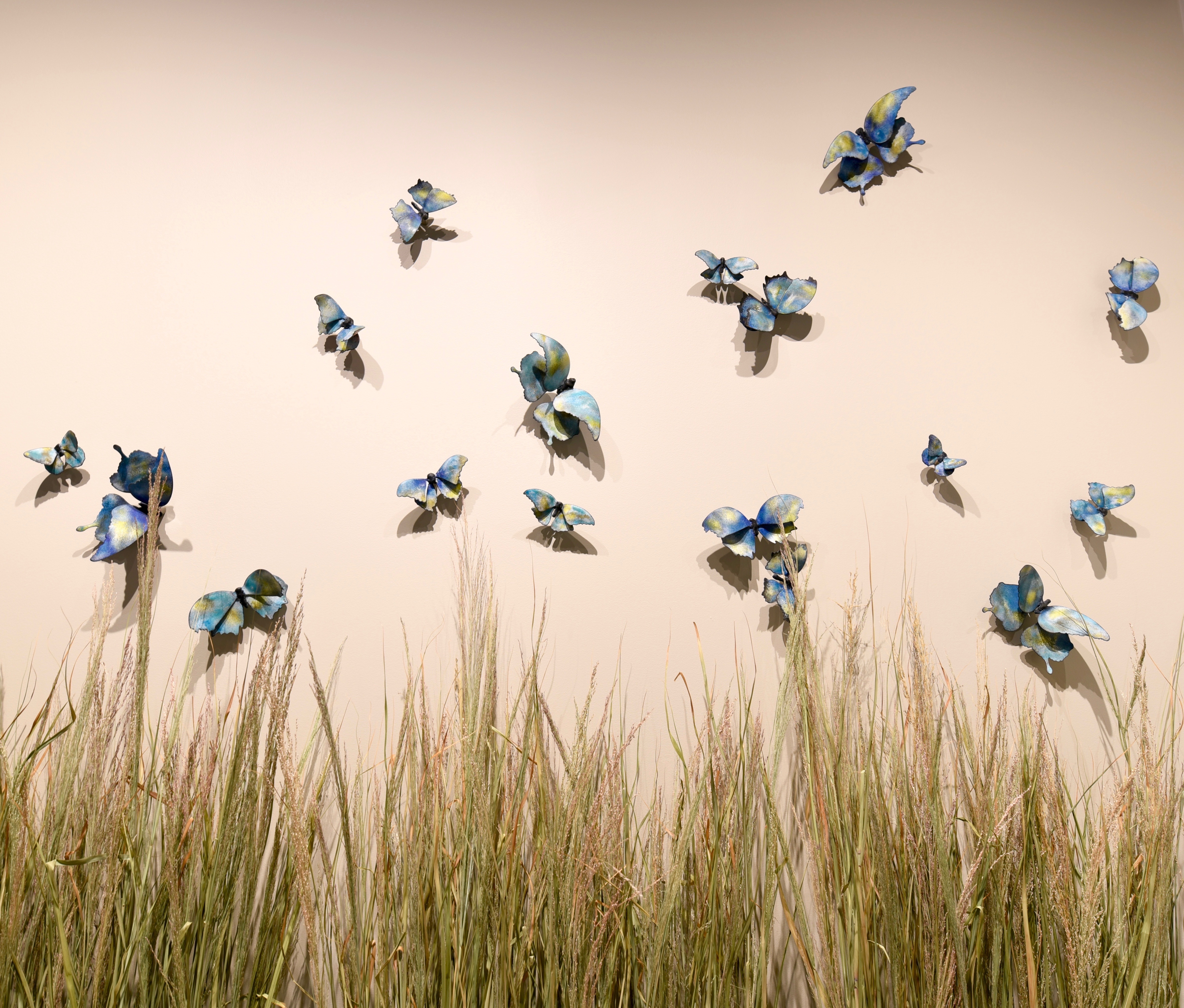 butterfly art hung on the wall above grass