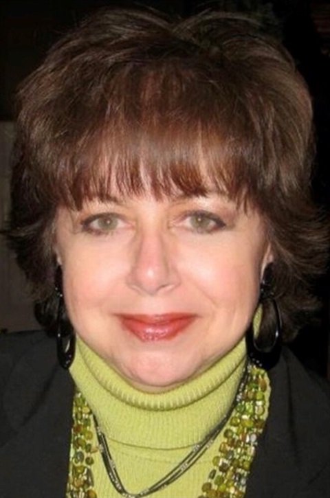 headshot of brunette woman with black jacket and lime sweater