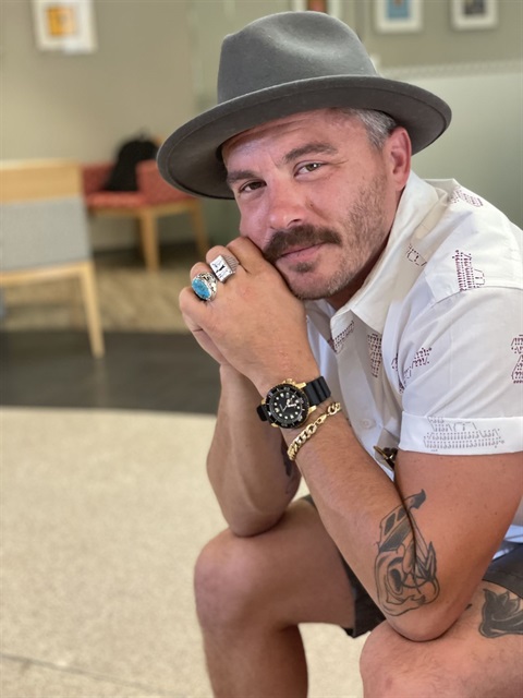 guy resting elbows on legs in brimmed hat