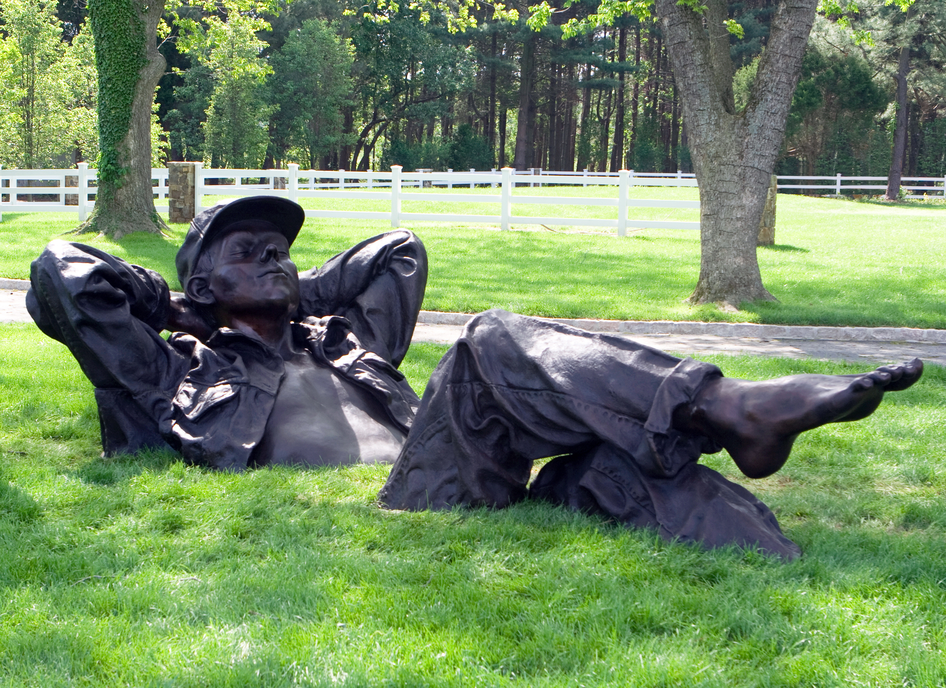 massive bronze sculpture of man sitting in the grass