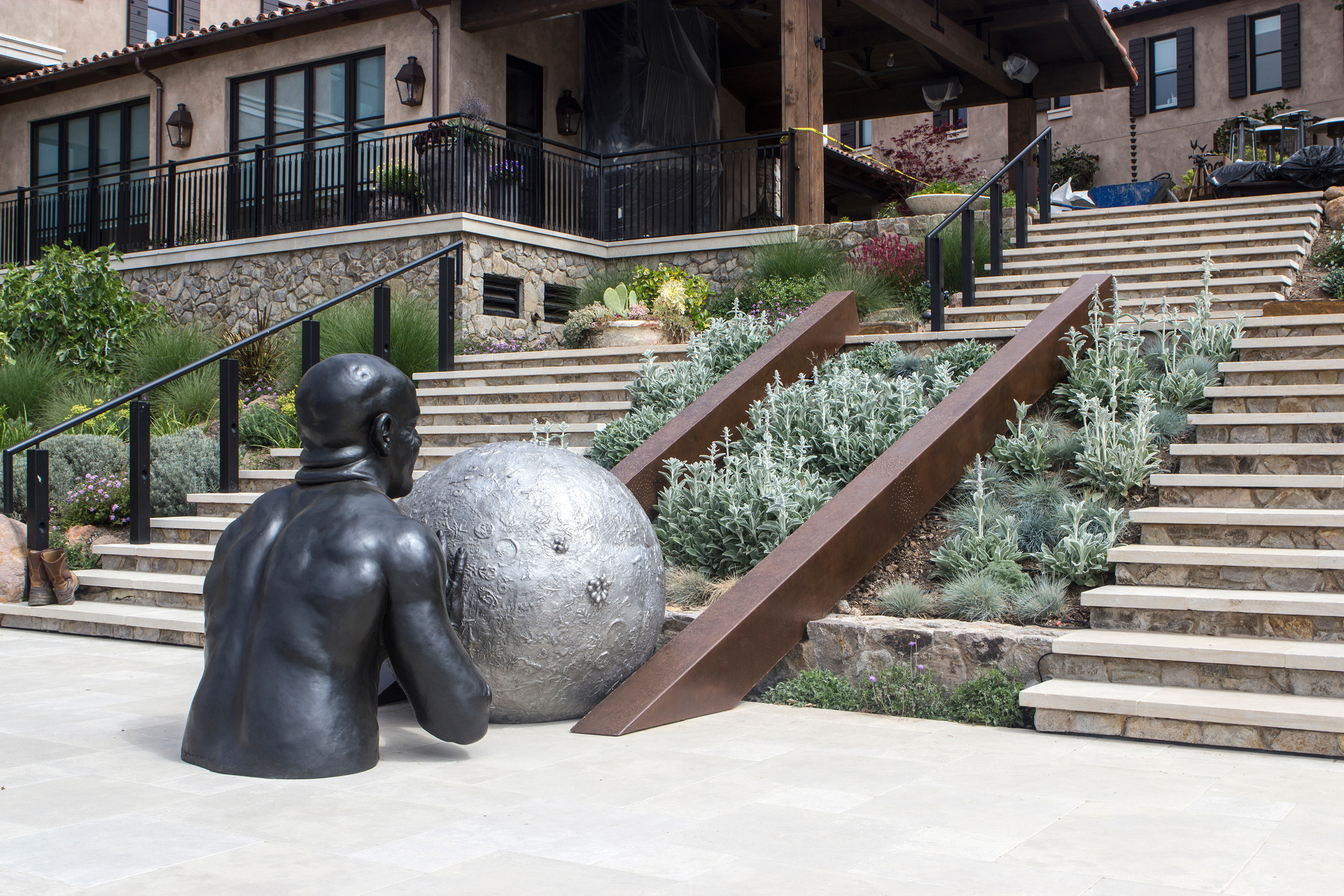 bronze statue of man pushing sphere up stairs