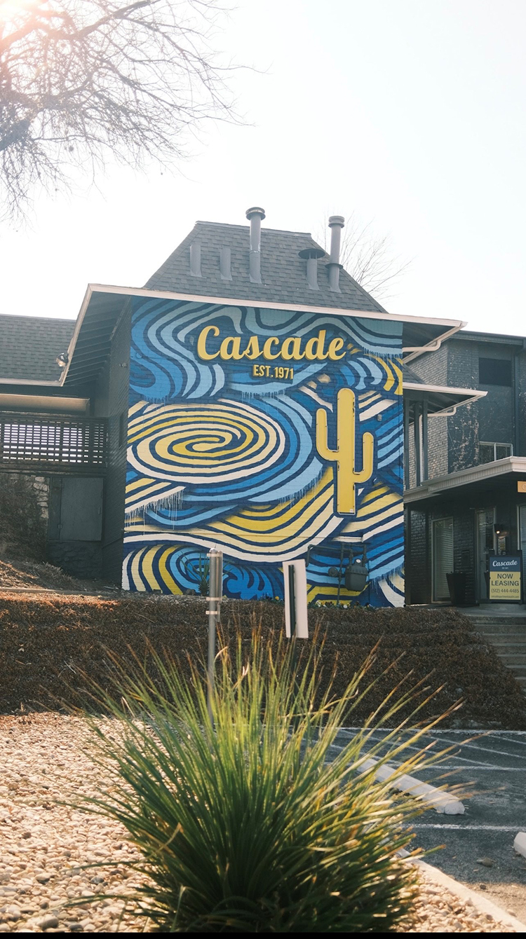 multi story blue and yellow mural with curves and cactus