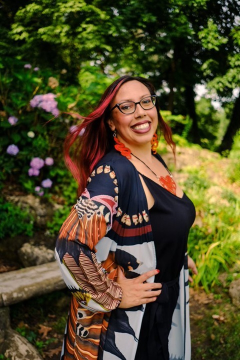 woman in printed dress with hand on hip smiling at the camera