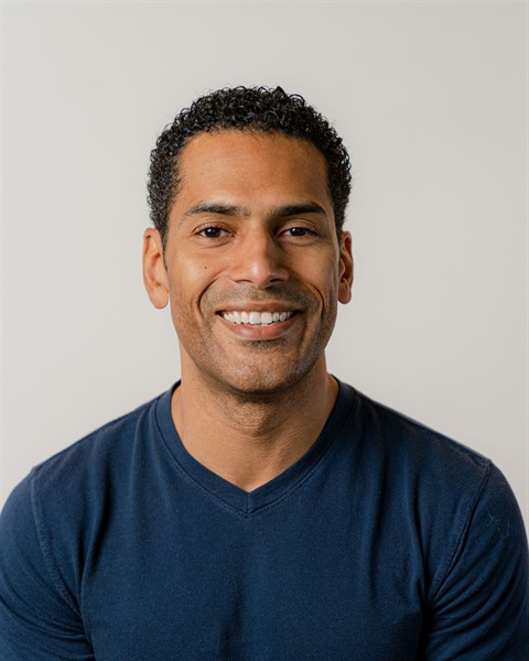 young black man in blue sweater smiling at camera