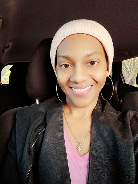 young tan woman with pink hat, pink shirt and black sweater