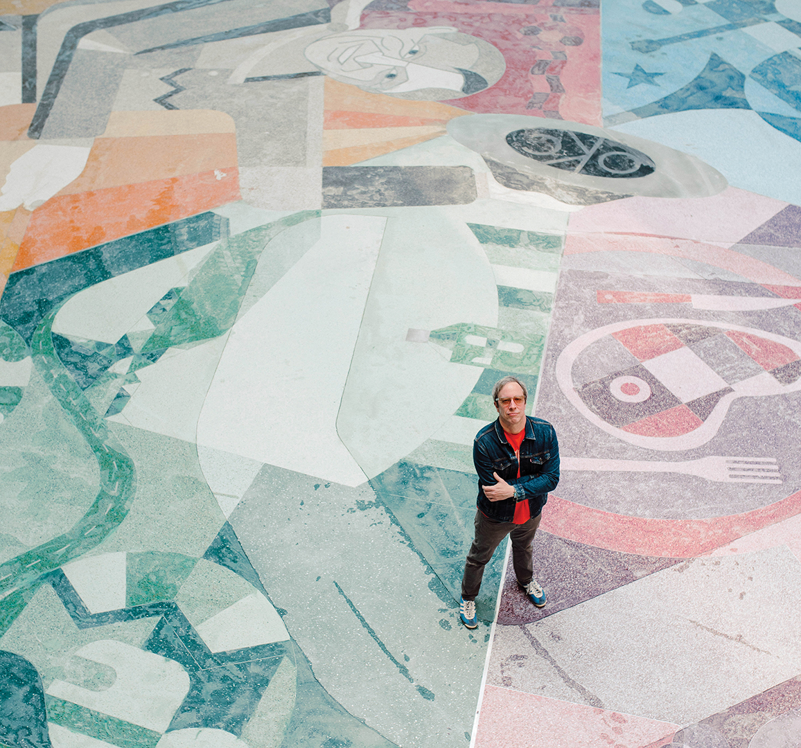 man standing on massive mosaic tile mural