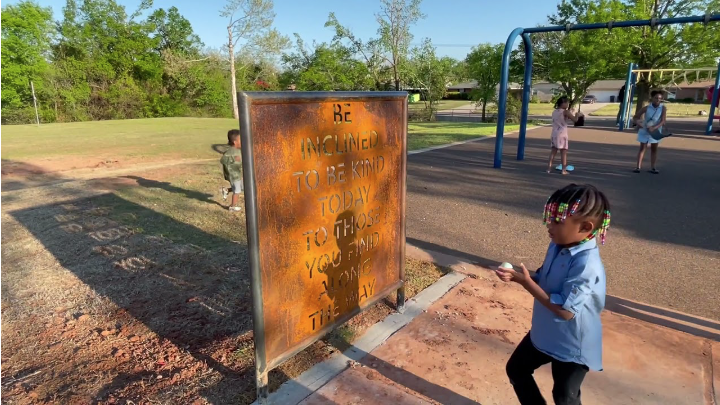 little kid playing at playground near written art