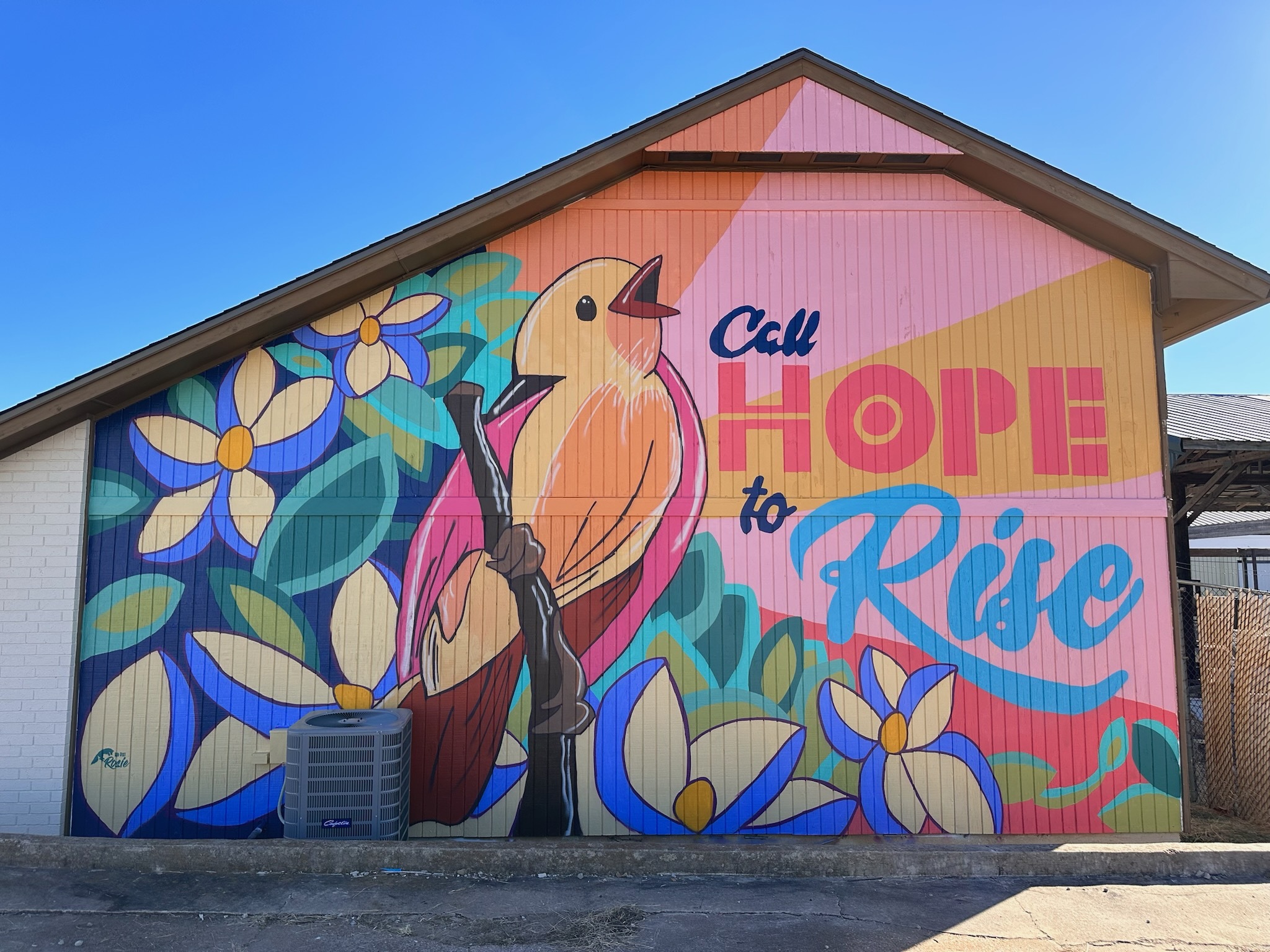 mural on side of building with bird on tree branch