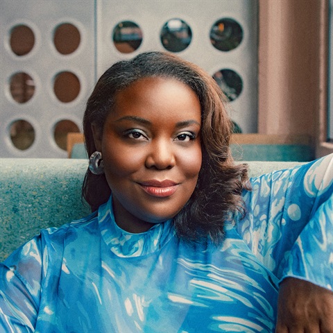 young black woman with shiny blue top smiling at the camera