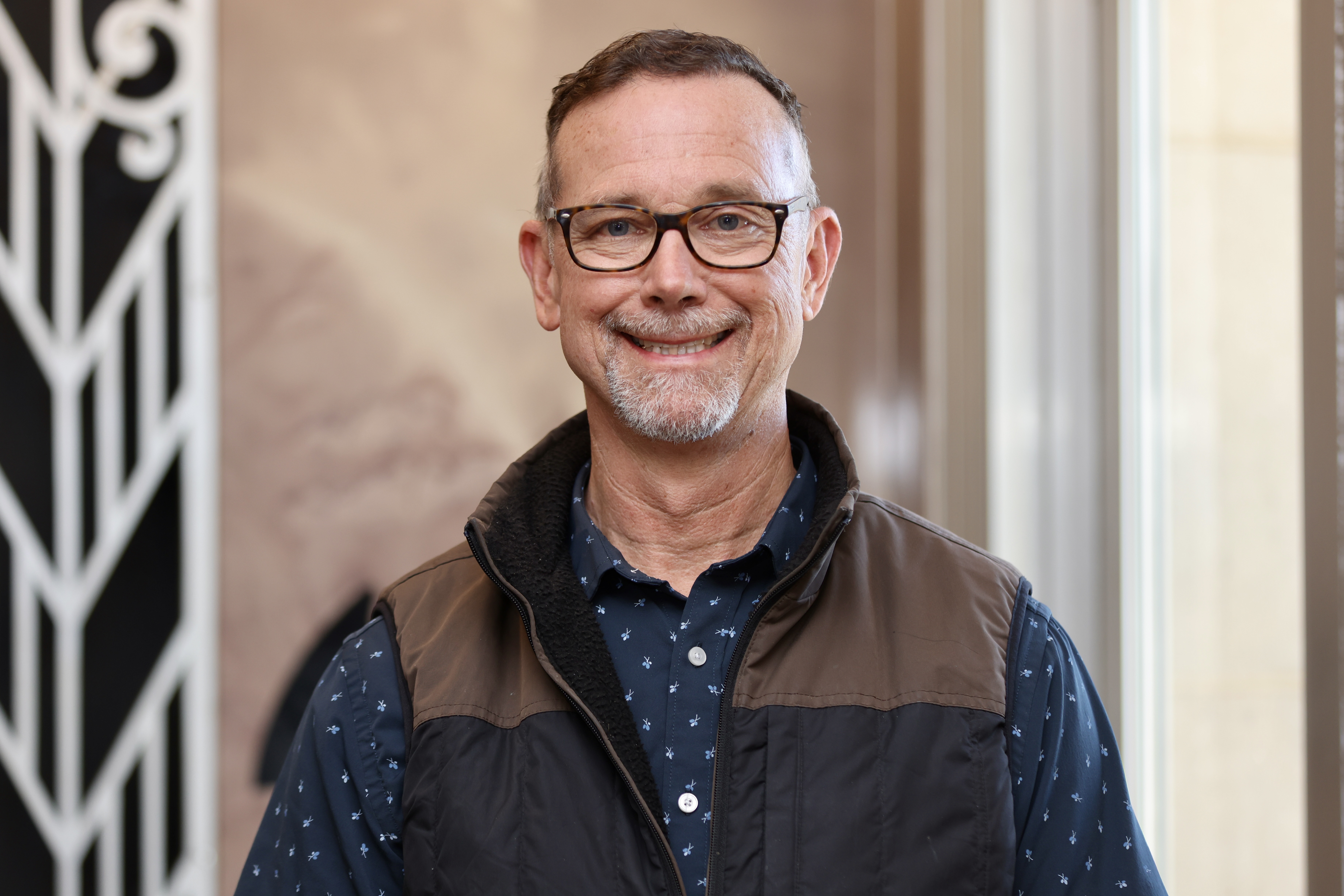 Gregory-Grimaud smiling wearing vest and polka dot shirt