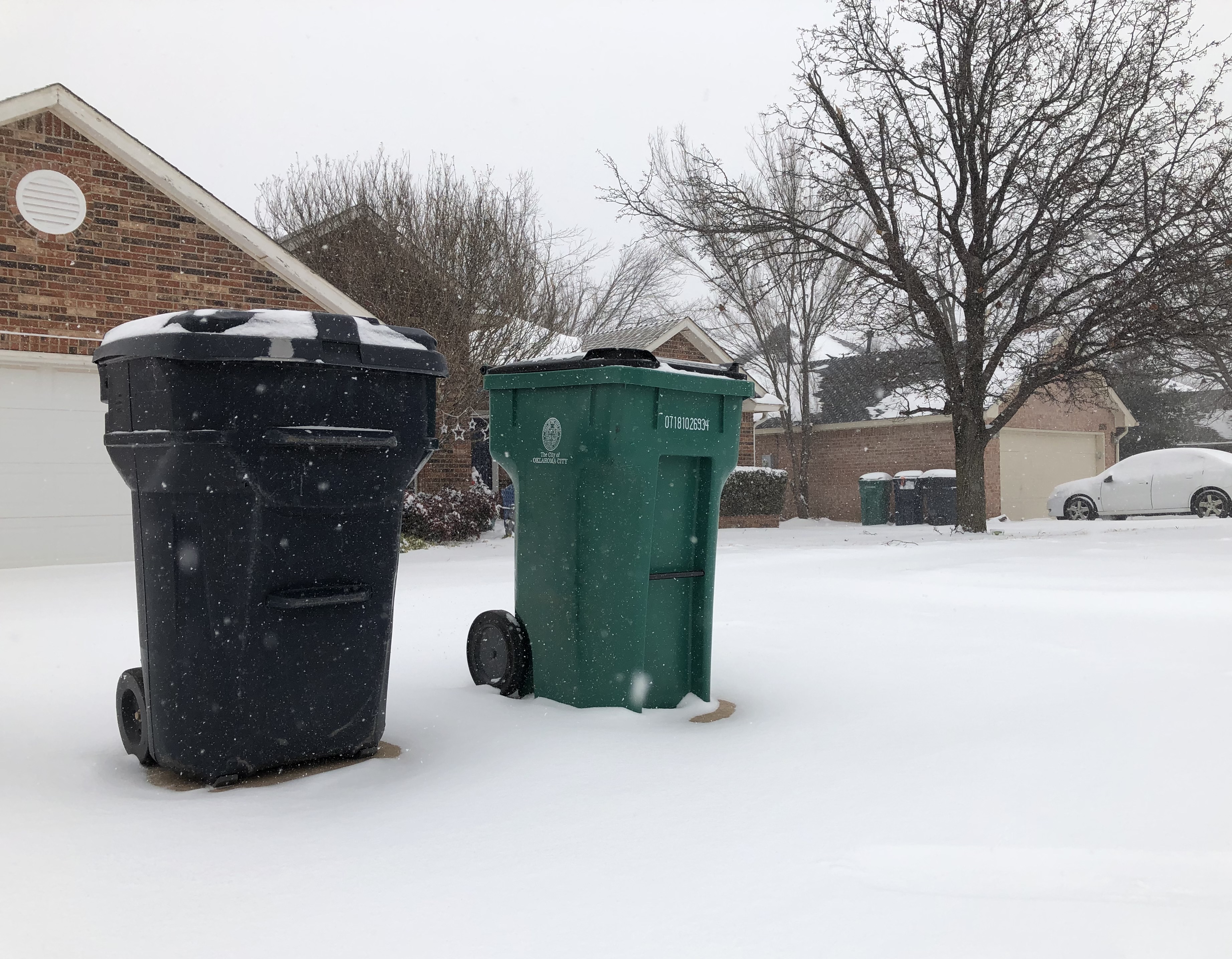 An OKC trash and recycling cart sit out during a winter snowstorm. 